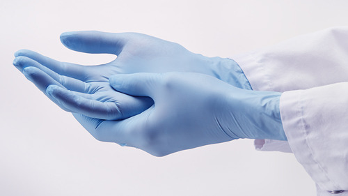 Two hands in light blue gloves, symbolizing StarGuard® Protect from Starlabs. A white lab coat is partially visible.